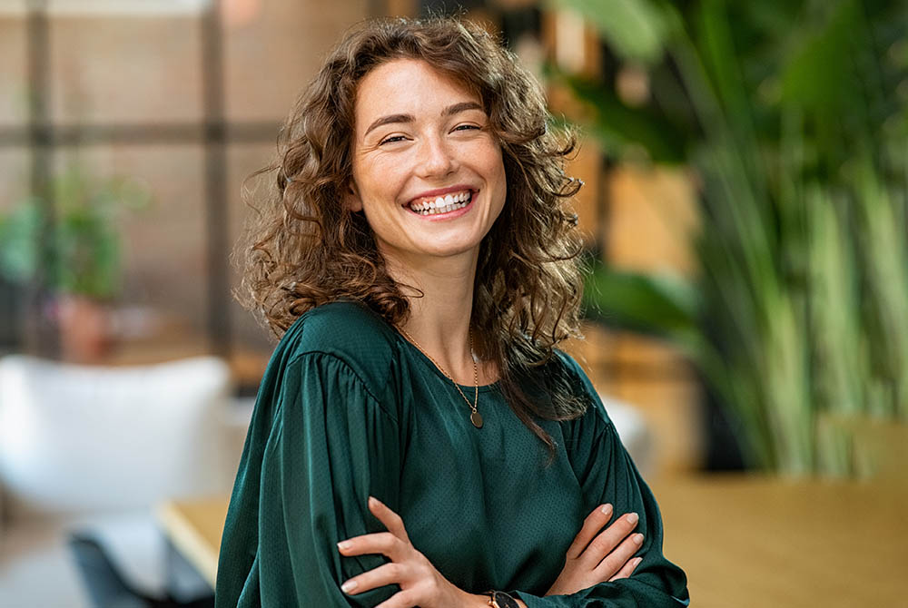 Beautiful woman smiling with crossed arms-1000x670