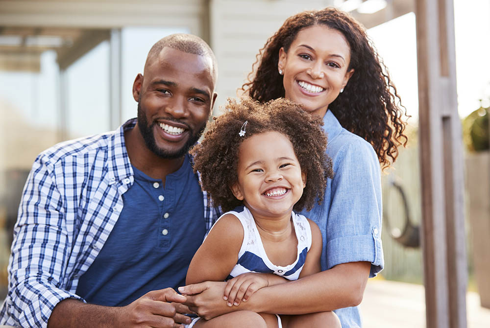 Young black family embracing outdoors and smiling at camera-1000x670