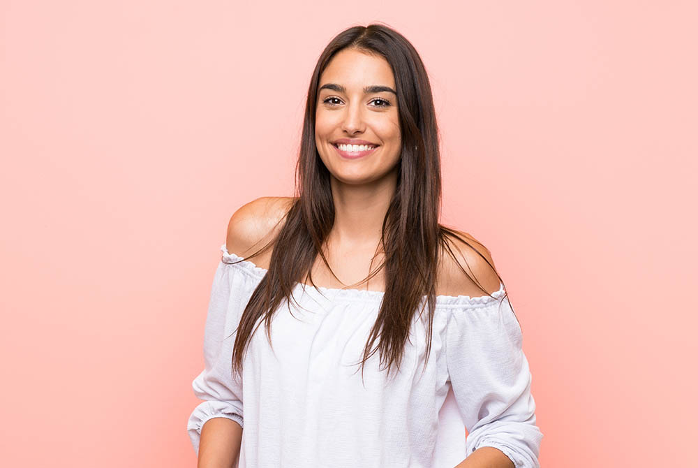 Young woman over isolated pink background laughing-1000x670